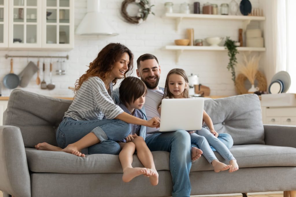 A happy family sitting on a couch looking at a laptop